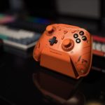 Orange gaming controller on desk with blurred background, ideal for tech enthusiasts. – affordable arc raiders pc