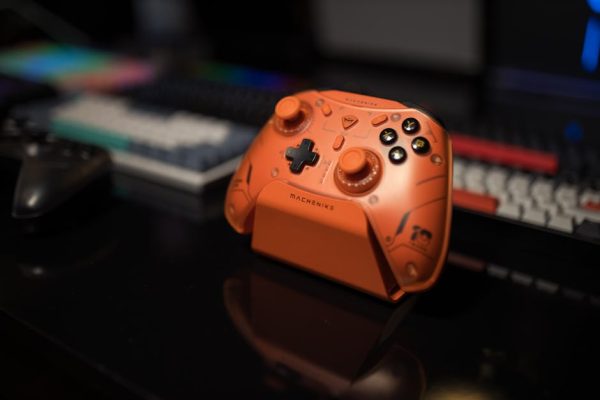 Orange gaming controller on desk with blurred background, ideal for tech enthusiasts. – affordable arc raiders pc