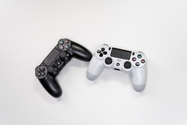 Flat lay of black and white gaming controllers against a white backdrop, perfect for gaming enthusiasts. – Assassin's Creed: Black Flag Resynced