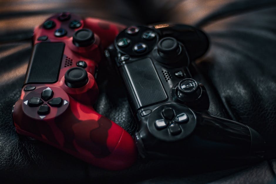 Red and black game controllers on a leather surface, focusing on technology and gaming.