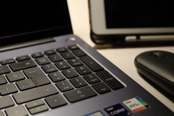 Close-up of laptop keyboard, wireless mouse, and tablet illustrating modern workspace technology. – ASUS ZenBook A16 review