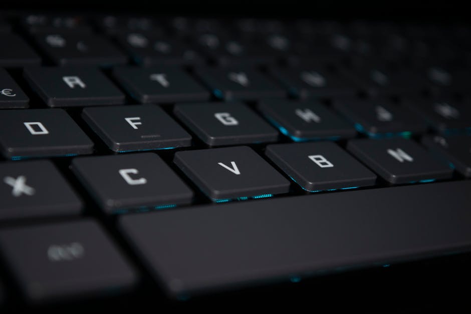 A close-up shot of a backlit keyboard in a dark setting, highlighting the keys.