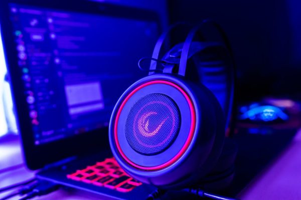 Close-up of gaming headset with neon lighting, placed next to a laptop. Perfect for tech and gaming themes. – gaming headsets for pc