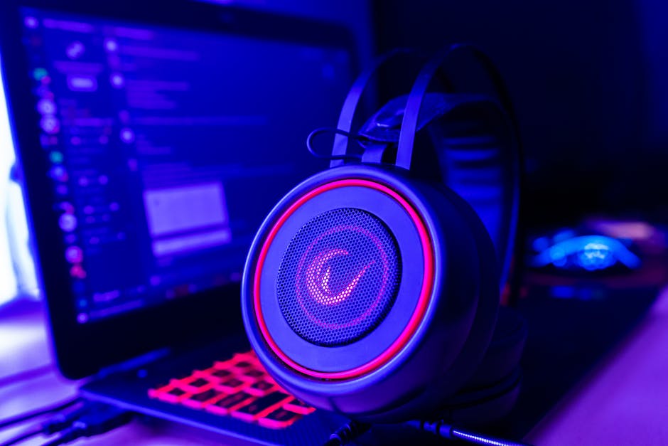 Close-up of gaming headset with neon lighting, placed next to a laptop. Perfect for tech and gaming themes. – gaming headsets for pc