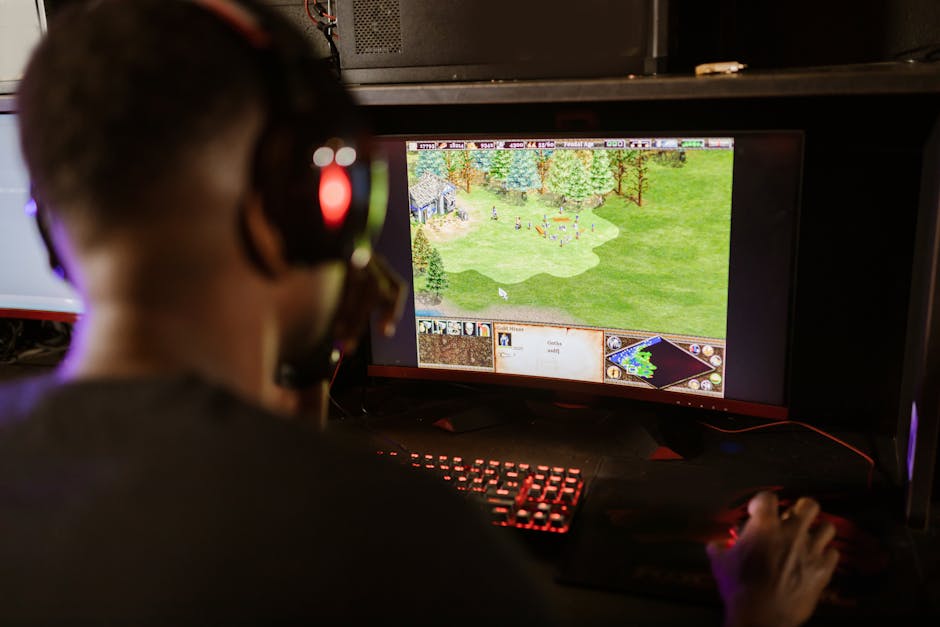 A gamer intensely playing a strategy game on a high-resolution monitor indoors.