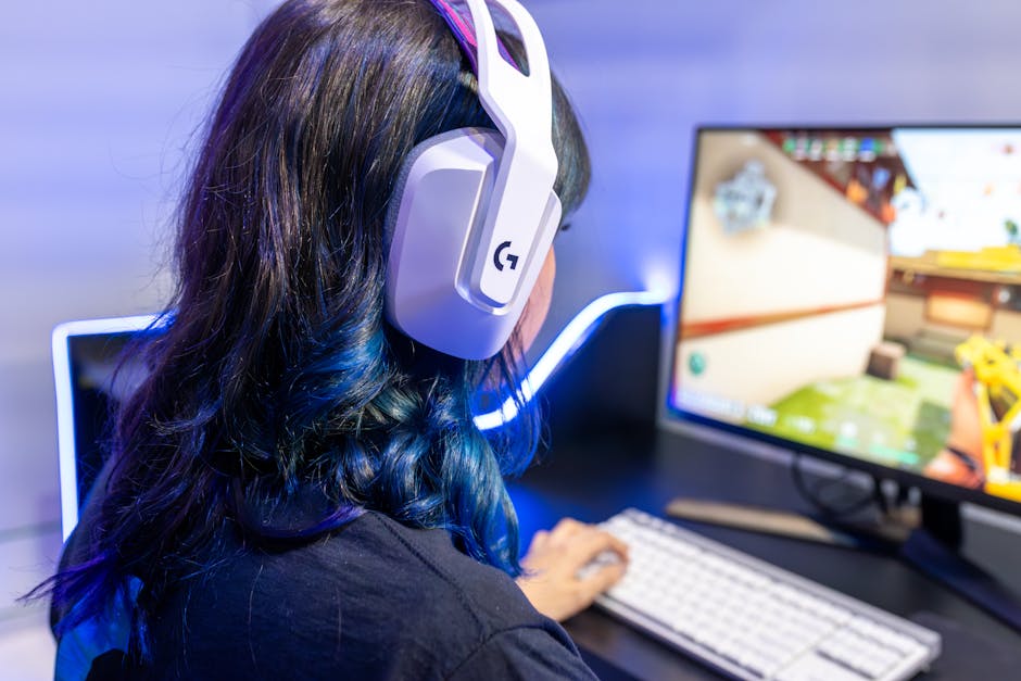 A young gamer playing an online game while wearing headphones, focused on the screen.