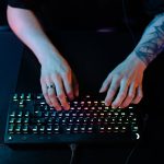 Close-up of hands typing on a RGB gaming keyboard with a tattooed arm and ring visible. – best gaming keyboards 2025