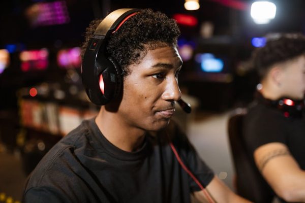 A young man wearing a headset intensely focused on gaming in a lively eSports arena. – best xbox gaming headset