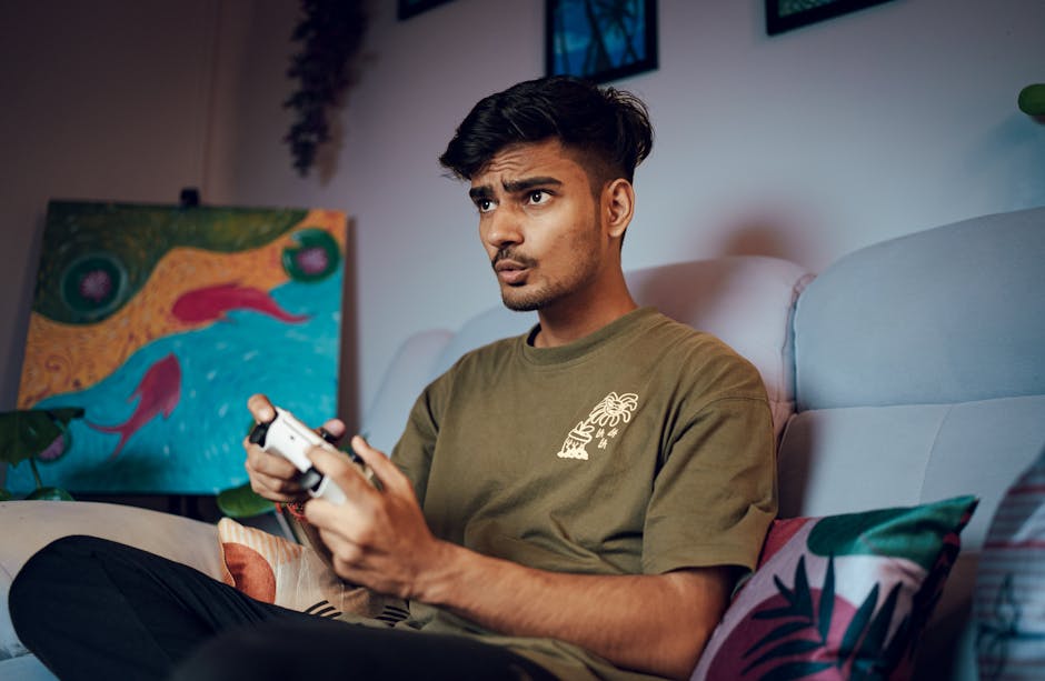 A young man focused on gaming indoors with a PS5 controller, enjoying modern digital entertainment.