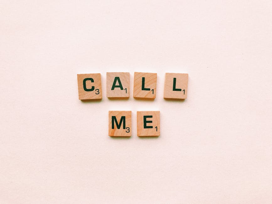 Wooden letter tiles spelling 'Call Me' on a pastel pink background, invoking communication and connection.