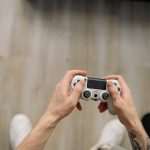 Overhead shot of hands with tattoos holding a game controller, ready for gaming. – DanielRPK ND Game Tease