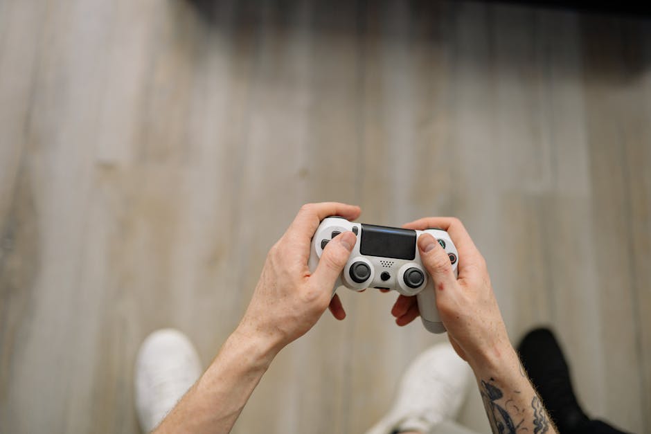 Overhead shot of hands with tattoos holding a game controller, ready for gaming. – DanielRPK ND Game Tease