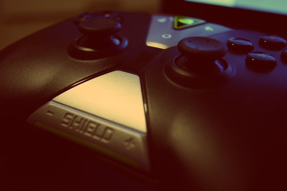 Close-up view of a modern gaming controller, highlighting joystick and buttons with a 'shield' design.