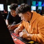 Two friends enjoying a video game session on an arcade machine indoors. – Fortnite Disney Partnership Impact