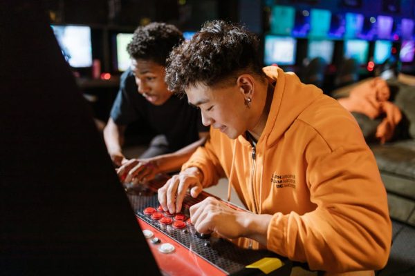 Two friends enjoying a video game session on an arcade machine indoors. – Fortnite Disney Partnership Impact