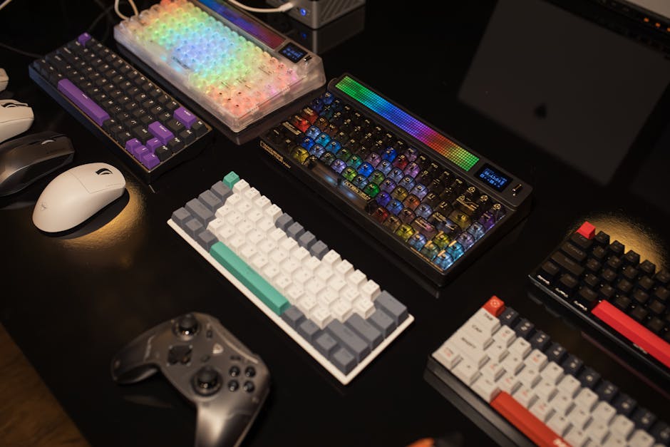 A collection of mechanical keyboards and gaming accessories displayed on a table, illuminated by vibrant RGB lighting.
