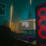 Atmospheric photo of a gaming setup with a glowing PC case and monitor displaying content editing software.