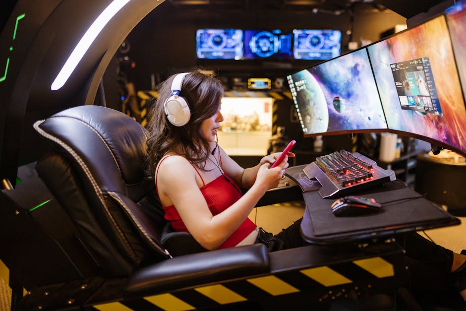 Young woman enjoying computer gaming at home with a high-tech gaming setup and smartphone.
