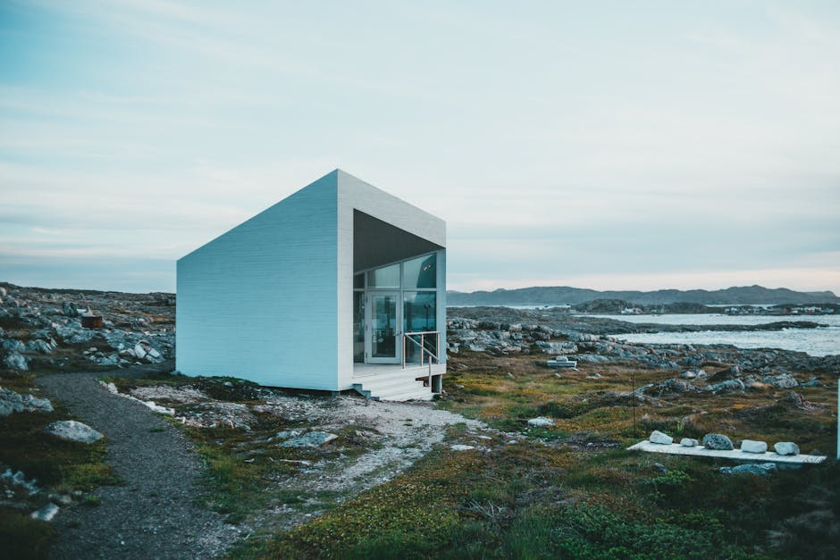 A sleek, modern tiny home located by a rocky coastline under a serene sky.