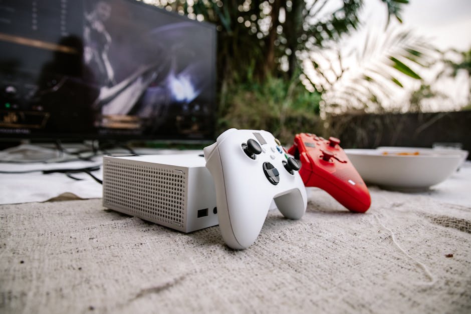 White and red game controllers on carpet with TV in the background, set outdoors.