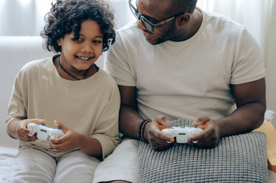 Cheerful crop African American child playing video game with joystick together with father sitting on sofa at home
