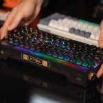 Hands adjusting an RGB mechanical keyboard among other keyboards on a desk. – split keyboard collection