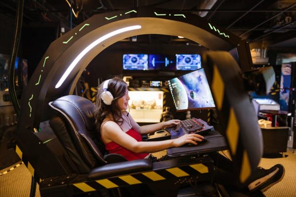 A woman plays a video game in a high-tech scorpion gaming chair, immersed in a modern arcade. – Subnautica 2 publisher change