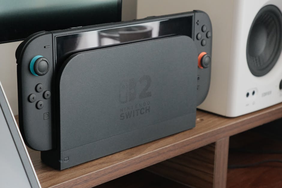 Nintendo console docked among speakers and a monitor on a wooden shelf.