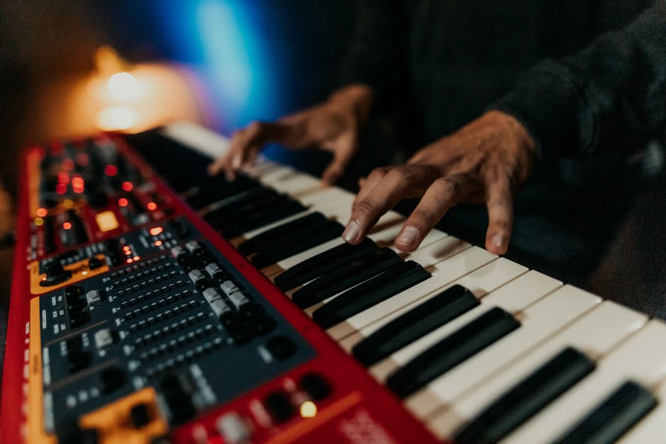 Close-up of hands playing a synthesizer keyboard in a moody, dimly lit environment. – best keyboards 2026
