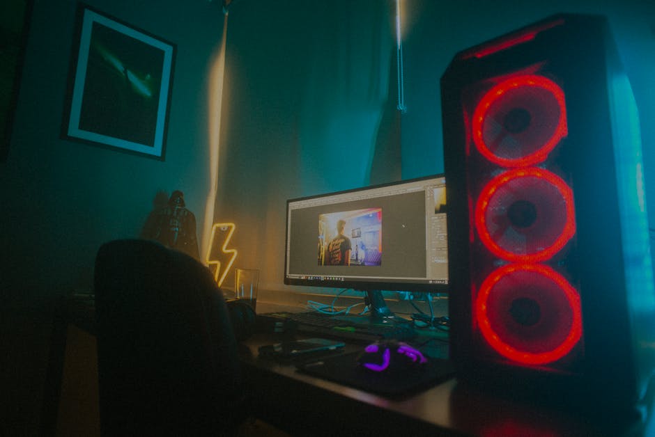 Atmospheric photo of a gaming setup with a glowing PC case and monitor displaying content editing software. – gaming pc help