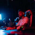 Gamers focused on their screens in a vibrant, dimly lit gaming environment. – esports titles, gaming longevity,
