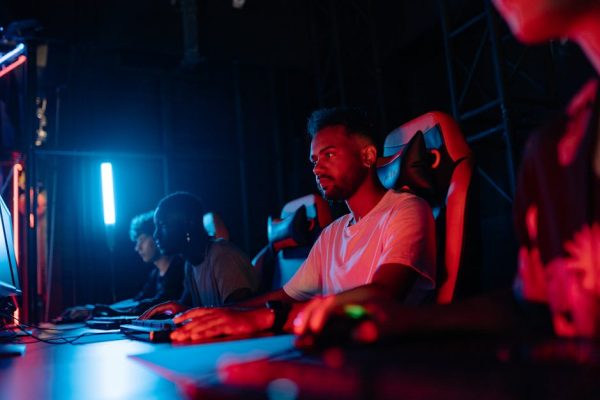 Gamers focused on their screens in a vibrant, dimly lit gaming environment. – esports titles, gaming longevity,