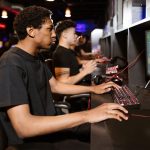 Group of young adults deeply engaged in competitive online gaming at a cyber cafe. – Yes impact on PC