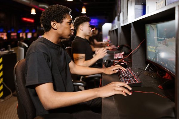 Group of young adults deeply engaged in competitive online gaming at a cyber cafe. – Yes impact on PC