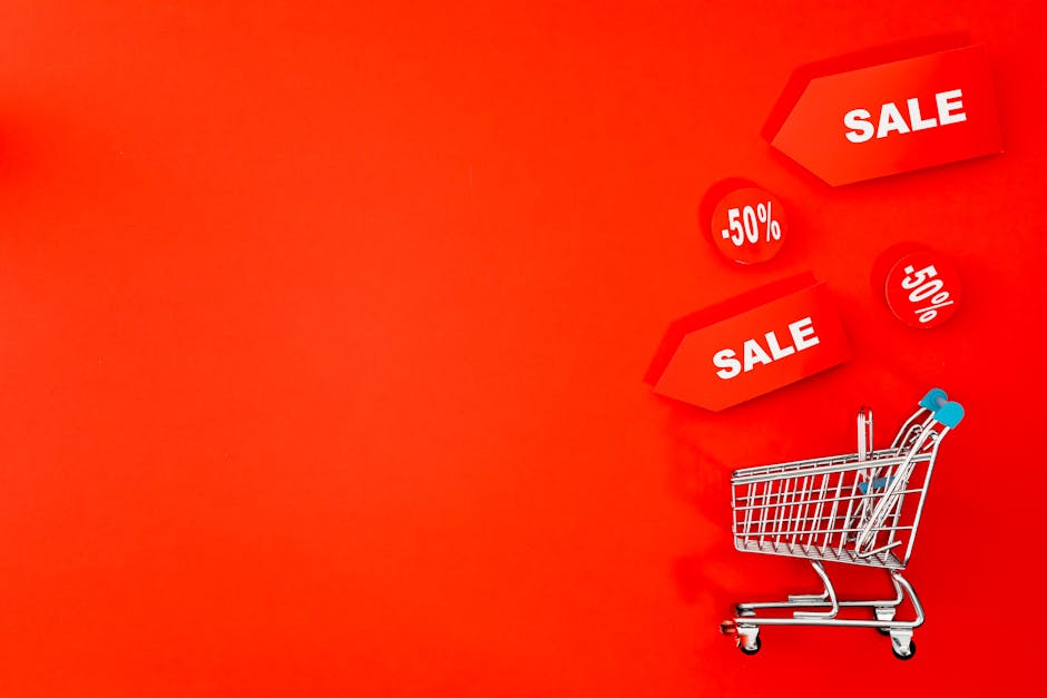 Shopping cart with sale tags on vibrant red backdrop promoting discounts.
